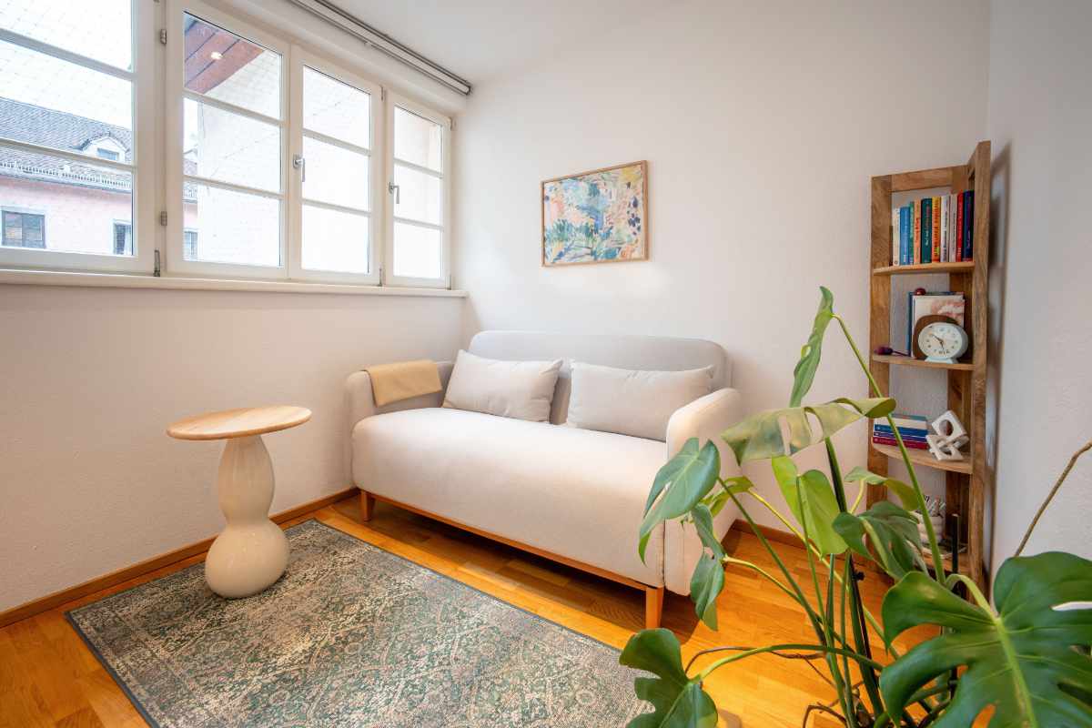 Heller Praxisraum für Psychotherapie in Innsbruck mit Fenstern, Holzboden, Teppich und Couch
